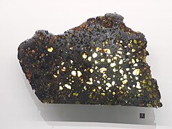 Crystals of olivine embedded in iron, in a slice of Esquel, a pallasite meteorite