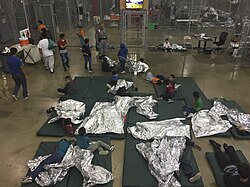 Children, sleeping mats, and foil blankets in wire mesh compartment, Ursula detention facility, June 2018