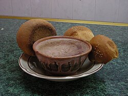 A cup of Oaxacan-style hot chocolate served in a traditional clay mug (with no handle) and pan de yema ('egg-yolk bread')