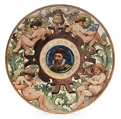 Faience commemorative plaque for Bernard Palissy by 19th-century artist John Eyre. The top-right cherub is painted holding a Palissy rusticware platter.