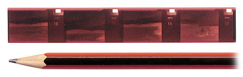 Negative strip of 110 film (with pencil for scale). The strip shown measures 111 mm × 16 mm (4.37 in × 0.63 in).