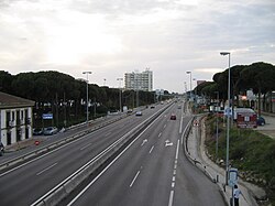 Jersey barriers may be used to separate the carriageways where the space is narrow. See this example near Málaga, Spain. There is also a bus stop in the bottom-right corner of the picture; it would not exist in a motorway.