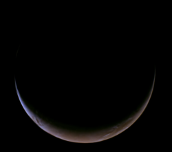 A color image of a crescent-shaped Mars, taken by the Psyche space probe as it approached the planet in May 2026.