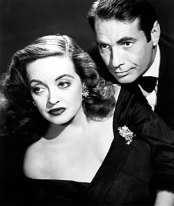 Davis posing as Margo Channing in a promotional image for All About Eve (1950): She is pictured with Gary Merrill, to whom she was married from 1950 to 1960, her fourth, and final, husband.