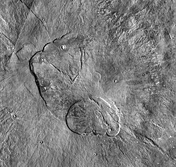 Central caldera complex of Alba Mons. The calderas are shallow compared to those on other Tharsis volcanoes. Within the larger caldera is a small shield capped by a concentric circular feature (near center). Image is about 200 km (120 mi) across (THEMIS daytime IR mosaic).