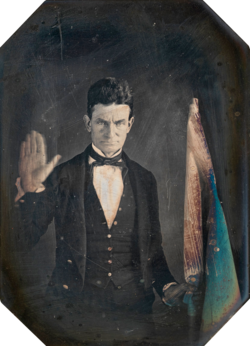 A daguerreotype of Brown taken by African-American photographer Augustus Washington in Springfield, Massachusetts, c. 1846–1847. Brown is holding the hand-colored flag of Subterranean Pass Way, his militant counterpart to the Underground Railroad.[88]