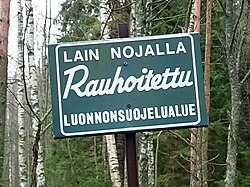 A conservation area's sign in the Finnish forest. It says, "A conservation area protected by law".