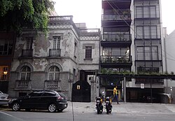 Dilapidated early 20th century home next to a modern apartment building. Roma has seen significant gentrification since the 2000s.