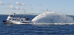 A Mackinac Island ferry passing in front of the Mackinac Bridge