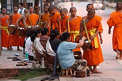 During Vesak, people give alms to monks (in the form of sticky rice) at dawn, in Luang Prabang, north Laos