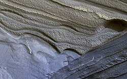 False color HiRISE view of water ice layers in Olympia Rupes, believed by scientists to be preserving climate conditions of Mars dating back millions of years. Depicted width: 1.3 km (3⁄4 mi)