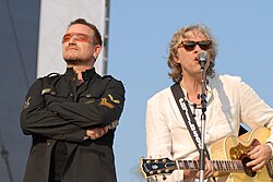 Geldof (right) persuaded a reluctant Bono to sing the line "Well, tonight thank God it's them, instead of you".[15]