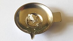 Peruvian flake cocaine on a metal milligram scale tray