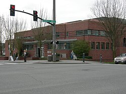 A brick building with slit-like windows seen from across a city street