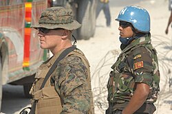 U.S. Marine Corps Cpl. Matt Kirkland and a United Nations peacekeeper from the Sri Lanka Army provide security for Haitian women receiving bags of rice for their families at a food distribution point in the city of Carrefour