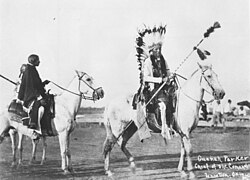 Quanah Parker on horseback wearing eagle feather headdress and holding a lance bottom-up. Late 1800s