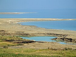 Sinkholes near the Dead Sea, formed when underground salt is dissolved by freshwater intrusion, due to continuing sea-level drop.