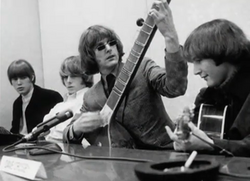 Byrds press conference in March 1966, with McGuinn playing sitar to illustrate the Indian classical music influences in "Eight Miles High".