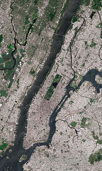 A satellite image of Manhattan, bounded by the Hudson River to the west, the Harlem River to the north, the East River to the east, and New York Harbor to the south, with rectangular Central Park prominently visible. Roosevelt Island, in the East River, belongs to Manhattan.