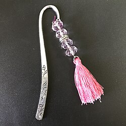 A metal bookmark with a fabric tassel and decorative beads