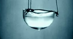 Liquefied helium. This helium is not only liquid, but has been cooled to the point of superfluidity. The drop of liquid at the bottom of the glass represents helium spontaneously escaping from the container over the side, to empty out of the container. The energy to drive this process is supplied by the potential energy of the falling helium.