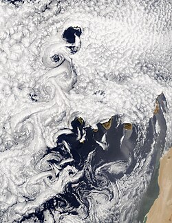 Downwind of obstacles, in this case, the Madeira and the Canary Islands off the west African coast, eddies create turbulent patterns called vortex streets.