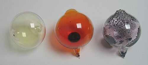 From left to right: chlorine, bromine, and iodine at room temperature. Chlorine is a gas, bromine is a liquid, and iodine is a solid. Fluorine could not be included in the image due to its high reactivity, and astatine and tennessine due to their radioactivity.