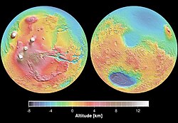 Mars Orbital Laser Altimeter (MOLA) colorized shaded-relief maps showing elevations in the western and eastern hemispheres of Mars. (Left): The western hemisphere is dominated by the Tharsis region (red and brown). Tall volcanoes appear white. Valles Marineris (blue) is the long gash-like feature to the right. (Right): Eastern hemisphere shows the cratered highlands (yellow to red) with the Hellas basin (deep blue/purple) at lower left. The Elysium province is at the upper right edge. Areas north of the dichotomy boundary appear as shades of blue on both maps.