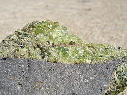 Forsterite var. peridot with minor pyroxene (brown) on vesicular basalt. Collected near Peridot, Arizona.