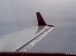 Rime ice on the leading edge of an aircraft wing. When the build-up is too large, the black deicing boot inflates to shake it off.[130][131]