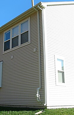 Part of a radon mitigation system including the fan and vent pipe is visible near the gutter downspout.