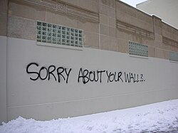 graffiti art on a wall stating "SORRY ABOUT YOUR WALL"