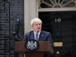 Boris Johnson stands behind a podium giving his resignation sppech