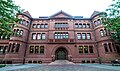 A large brick academic building. It has some ornate decorations, and two rounded sections separate the central portion from wings on either side.