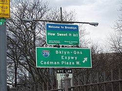 Rectangular blue-and-green sign reading, "Welcome to Brooklyn. How sweet it is!"