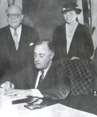 Frances Perkins looks on as Roosevelt signs the National Labor Relations Act.