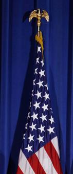 A U.S. flag with gold fringe and a gold eagle on top of the flag pole