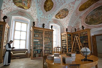 A Catholic monk reading in a monastery library