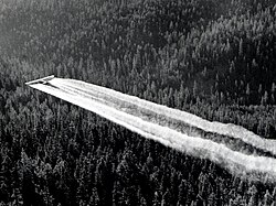An airplane spraying DDT over Baker County, Oregon as part of a spruce budworm control project, 1955