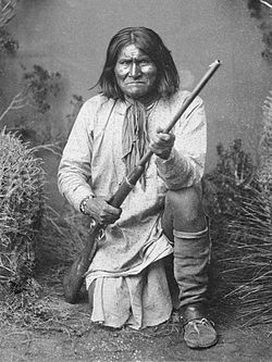 Geronimo (Goyaałé), a Bedonkohe Apache, kneeling with rifle, 1887