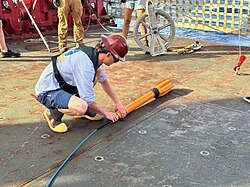 A marine technician preparing a towed magnetometer for deployment from a ship