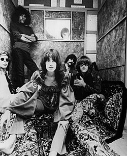 Publicity photo of Jefferson Airplane, 1967. From left: Jack Casady, Jorma Kaukonen, Grace Slick, Marty Balin (seen in window frame), Spencer Dryden, Paul Kantner.