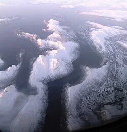 Snow-covered mountains stand out in contrast to the dark water Efjorden fjord and Stefjorden, Tysfjorden and Ofotfjorden fjords in the distance.