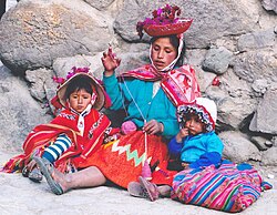 Quechua woman spinning wool in Peru, with children