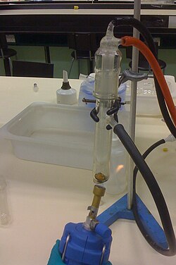 Camphor subliming in a cold finger. The crude product in the bottom is dark brown; the white purified product on the bottom of the cold finger above is hard to see against the light background.