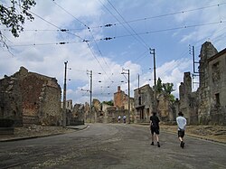 Ruined stone buildings lining an empty street in Oradour-sur-Glane