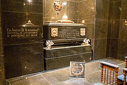 The grave of Emperor Pedro I of Brazil (who was also King of Portugal as Pedro IV) and those of his wives, Maria Leopoldina (not pictured, opposite his grave) and Amélie (left), are made of green granite. The walls as well as the floor are clad in the same material.[75] The crypt is located beneath the Monument to the Independence of Brazil