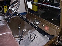 In the Ford Model T the left-side hand lever sets the rear wheel parking brakes and puts the transmission in neutral. The lever to the right controls the throttle. The lever on the left of the steering column is for ignition timing. The left foot pedal changes the two forward gears while the centre pedal controls reverse. The right pedal is the brake.