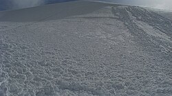 15 cm deep, soft slab avalanche triggered by a snowboarder near Heliotrope Ridge, Mount Baker in March 2010. Multiple crown fracture lines are visible in the top-middle of the image. Note the granular characteristic of the debris in the foreground that results from the slab breaking up during descent.