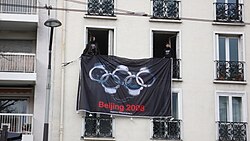 Protest action in Paris, April 2008, displaying a 'Reporters Without Borders (RSF)' flag depicting the Olympic rings in the form of handcuffs or padlocks, along with the legend 'Beijing 2008'